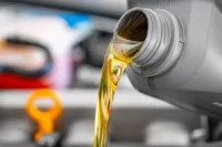 Importância de trocar o óleo do carro representado com um óleo sendo depositado em um carro.