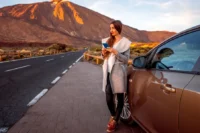 Cuidados ao viajar de carro representado por uma mulher em uma estrada com um carro.