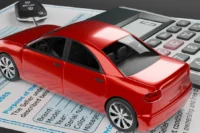 Imposto sobre veículos representado por um carro vermelho com uma calculadora ao lado.