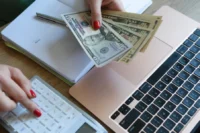 Carros com o seguro mais barato representado por dinheiro, um computador, uma calculadora e um bloco de notas.