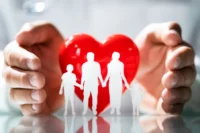 Duas mãos protegendo uma família representando como funciona o seguro de vida.