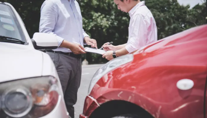 pt em carro financiado sem seguro sendo representado por uma colisão de dois carros e uma pessoa assinando alguns papeis