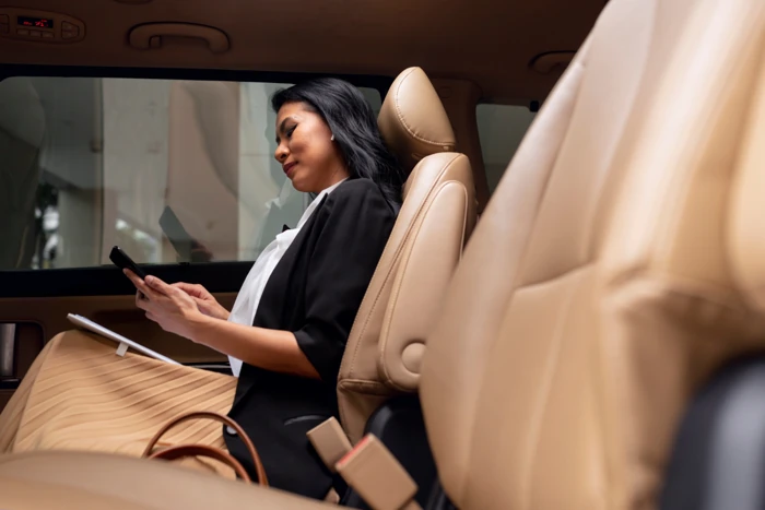 Mulher sentada no interior de um veículo que tem bancos de couro. Quanto custa colocar bancos de couro no carro?
