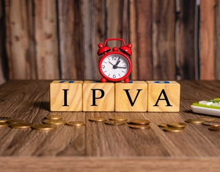 Cubos formando a palavra IPVA. Acima deles está um despertador. Falando de como pagar IPVA do carro pela internet.