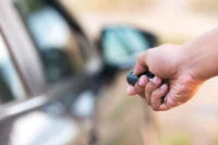 Homem aciona alarme de carro com controle remoto. Ensinando como declarar indenização de seguro de automóvel.