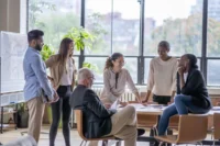 Grupo de colaboradores de uma empresa reunidos em uma sala. Veja como funciona o seguro de vida em grupo.