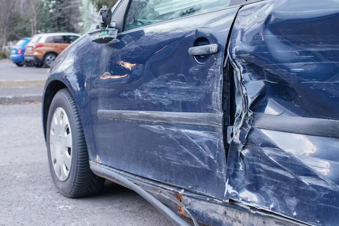 Carro azul com lateral danificada após receber "encostão". Falando sobre "encostei em um carro no estacionamento".