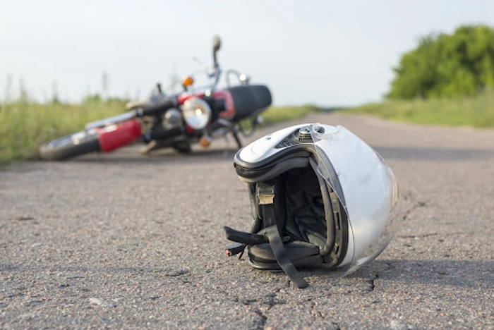 Moto caída no chão. Há um capacete também caído, em primeiro plano. Falando sobre seguro dpvat valor da indenização.