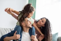Familia feliz brinca em casa. Explicando quem é o sinistrado no seguro de vida.