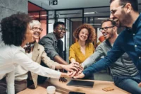 Grupo de colegas de trabalho dá as mãos. Falando sobre o seguro de vida em grupo valor da indenização.