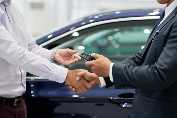 Corretor e cliente apertam as mãos. Corretor entrega uma chave de carro ao cliente. Falando sobre as melhores seguradoras de carros.