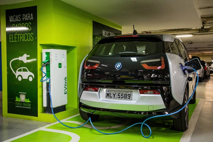 Moderno carro elétrico da BMW carregando em estacionamento. Falando sobre se seguro de carro elétrico é mais caro.