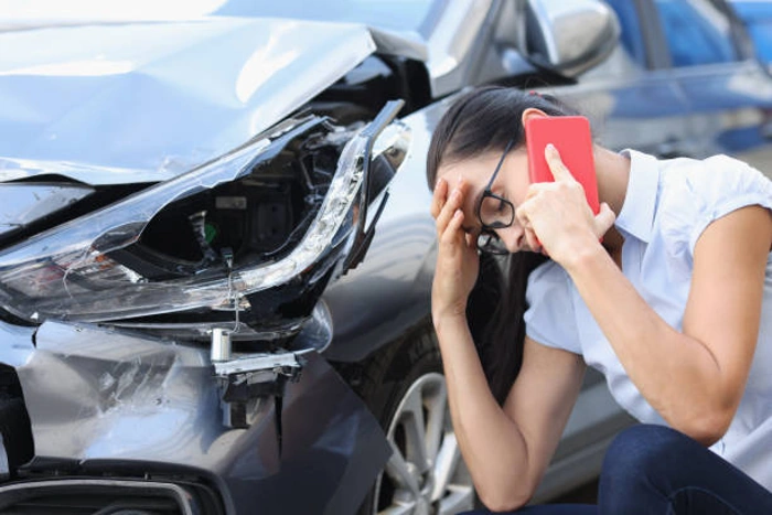 Mulher preocupada ligando para o socorro após bater seu carro. Falando sobre "quando bate o carro tem que fazer boletim de ocorrência".