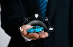 Homem com carro em miniatura na cor azul na palma da sua mão. Sobre essa miniatura, alguns símbolos digitalmente incluídos. Falando sobre os melhores seguros de carros.