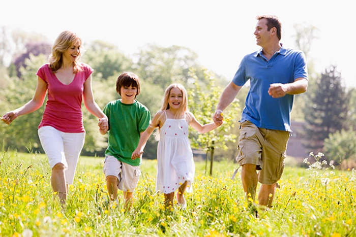 Família feliz brincando no parque. Falando sobre os benefícios do seguro de vida.