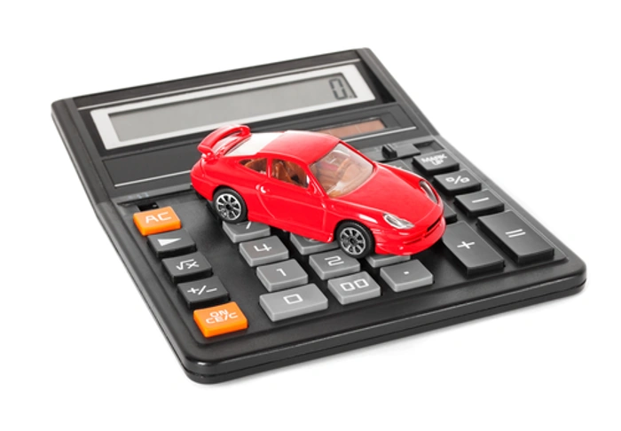 Miniatura de carro na cor vermelha sobre calculadora. Falando sobre o que encarece um seguro de automóvel.